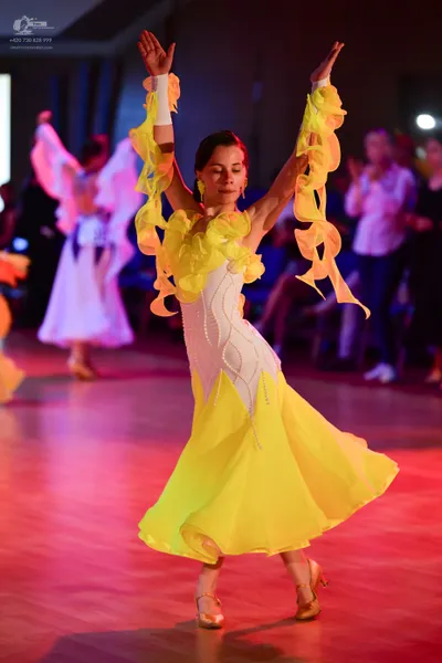 Dancesport competitor: Female dancer 1: yellow and white latin dance dress with large yellow ruffles on