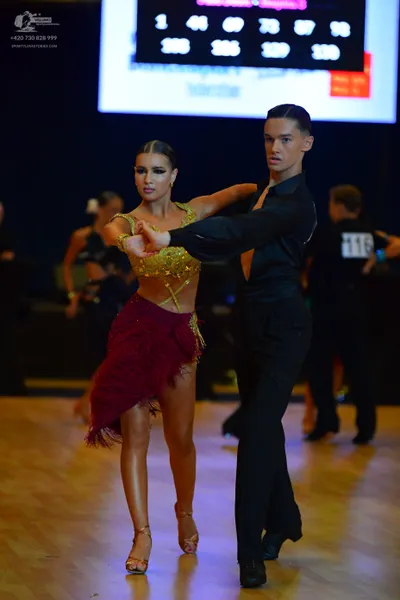 Dancesport competitor #116: Female dancer: gold sequin crop top and maroon fringe Latin skirt with tan dance