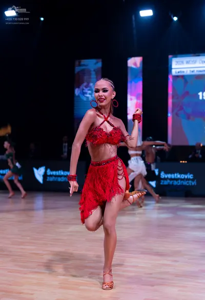 Dancesport competitor: Female dancer (foreground): red Latin dress with fringe and sequin/bead embellis