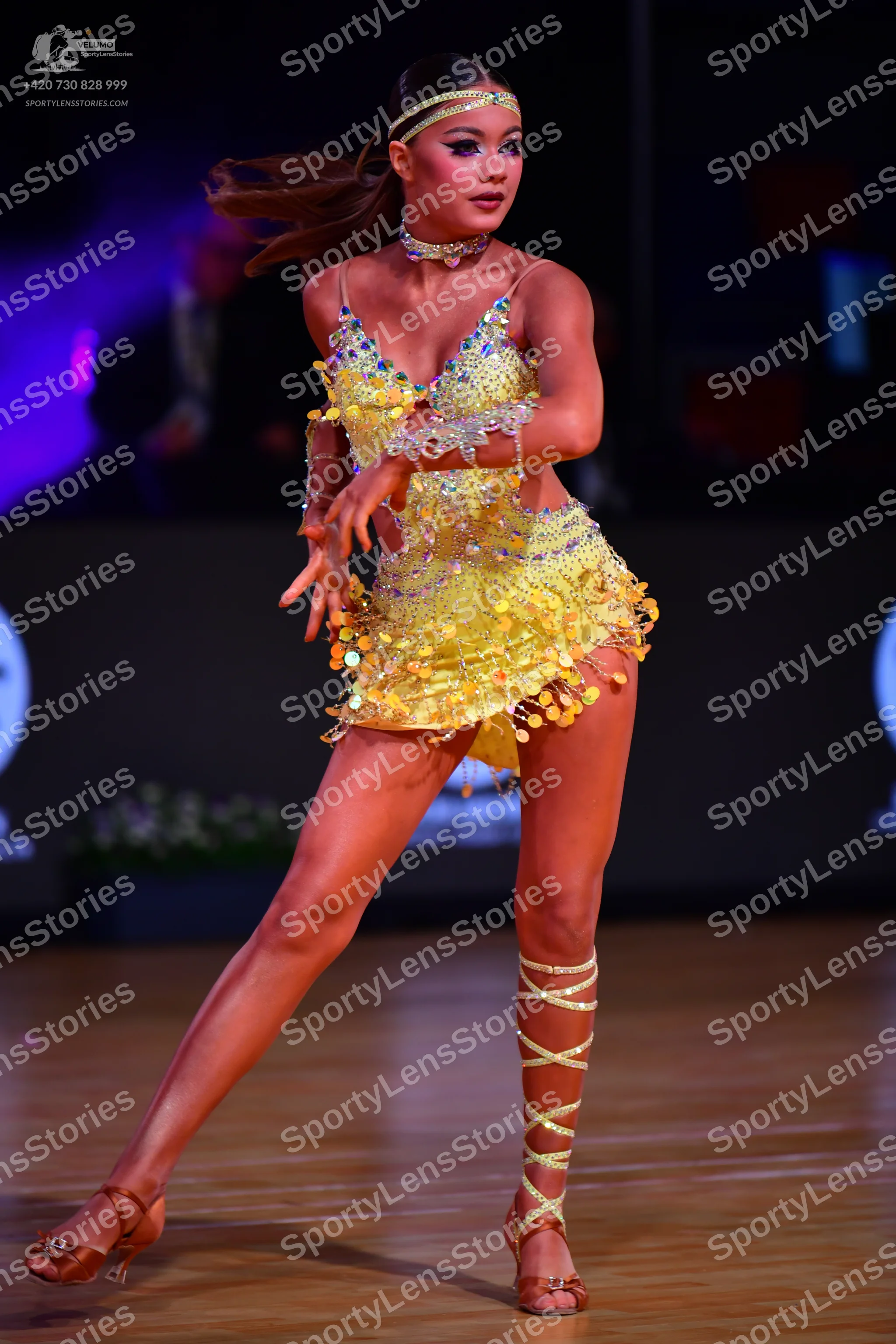 Dancesport competitor: Female dancer: yellow latin dress covered in gold sequins and small scales, with