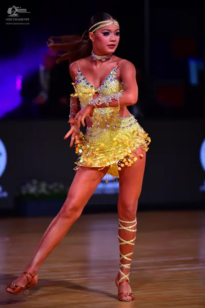 Dancesport competitor: Female dancer: yellow latin dress covered in gold sequins and small scales, with