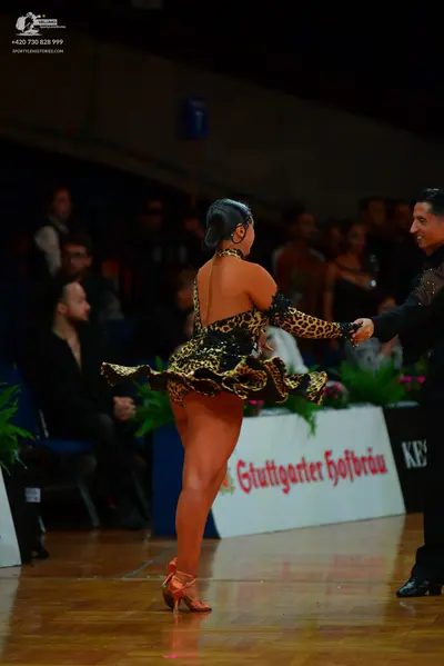 Dancesport competitor: Female dancer: leopard print Latin dance dress with a ruffled skirt and tan danc