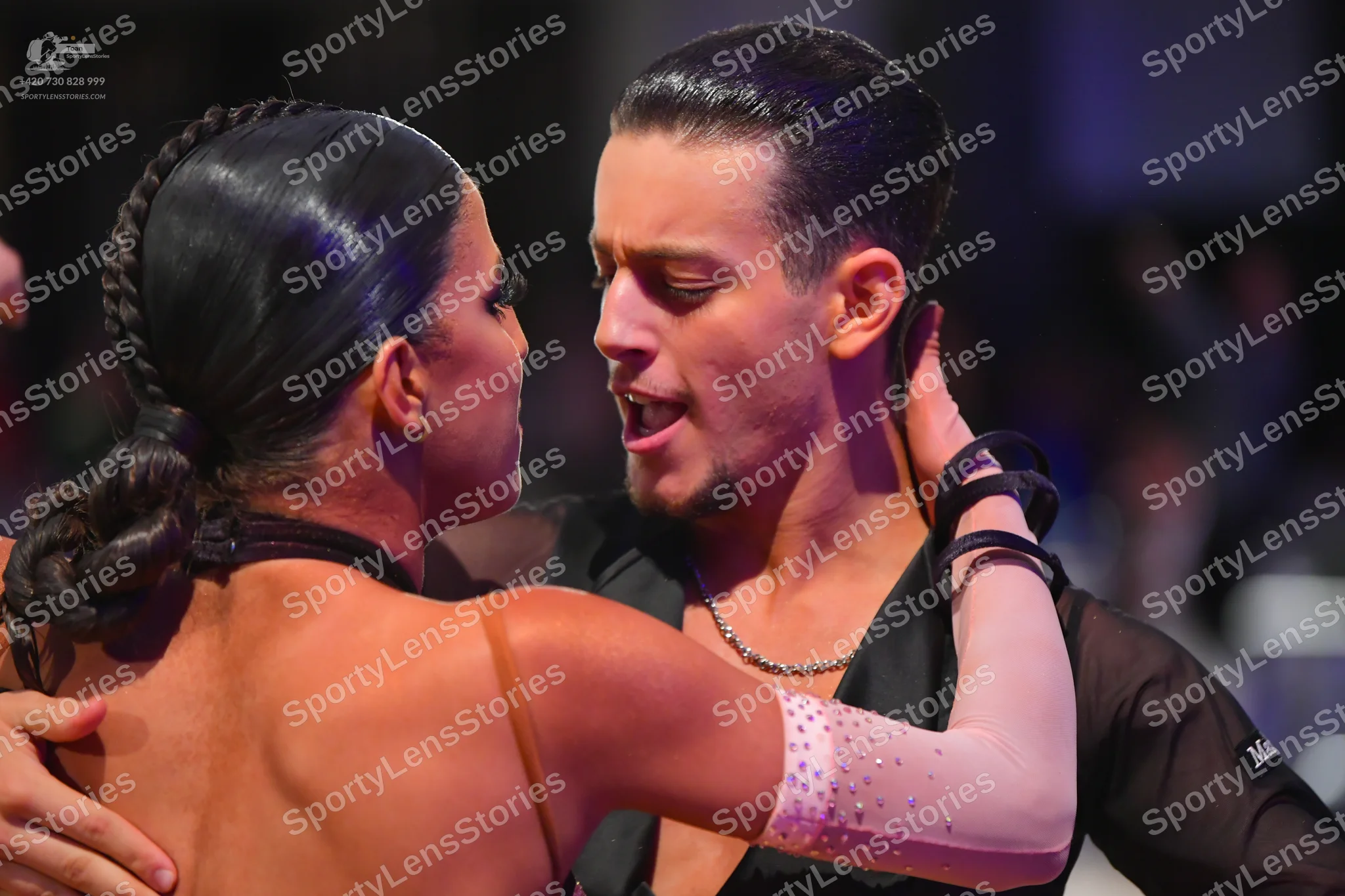 Dancesport competitor: Male dancer: black shirt with a slight sheen, wearing a silver chain necklace