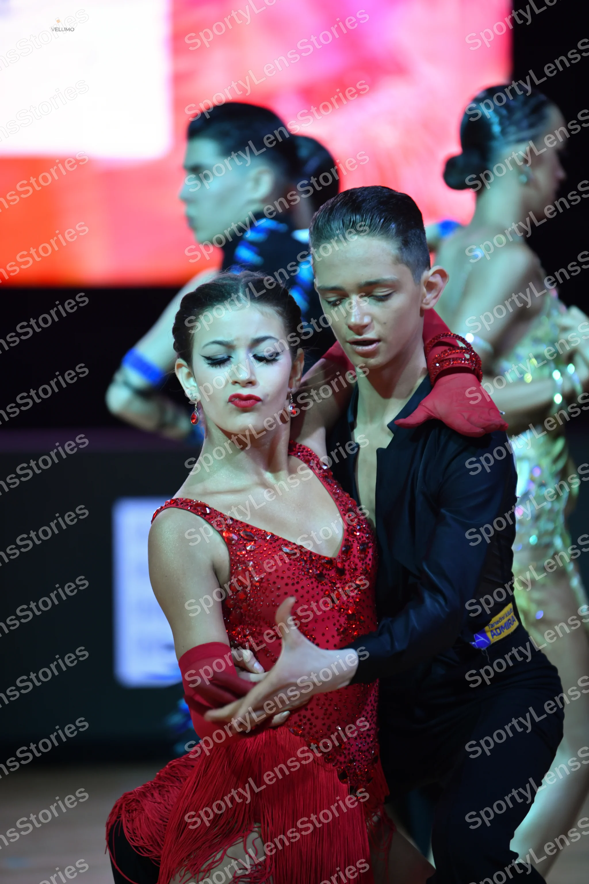 Dancesport competitor: Main female dancer: red Latin dress with a sequined bodice, fringe skirt, and re