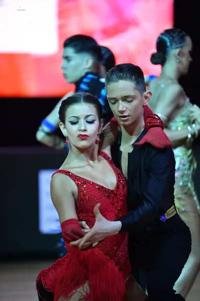Dancesport competitor: Main female dancer: red Latin dress with a sequined bodice, fringe skirt, and re
