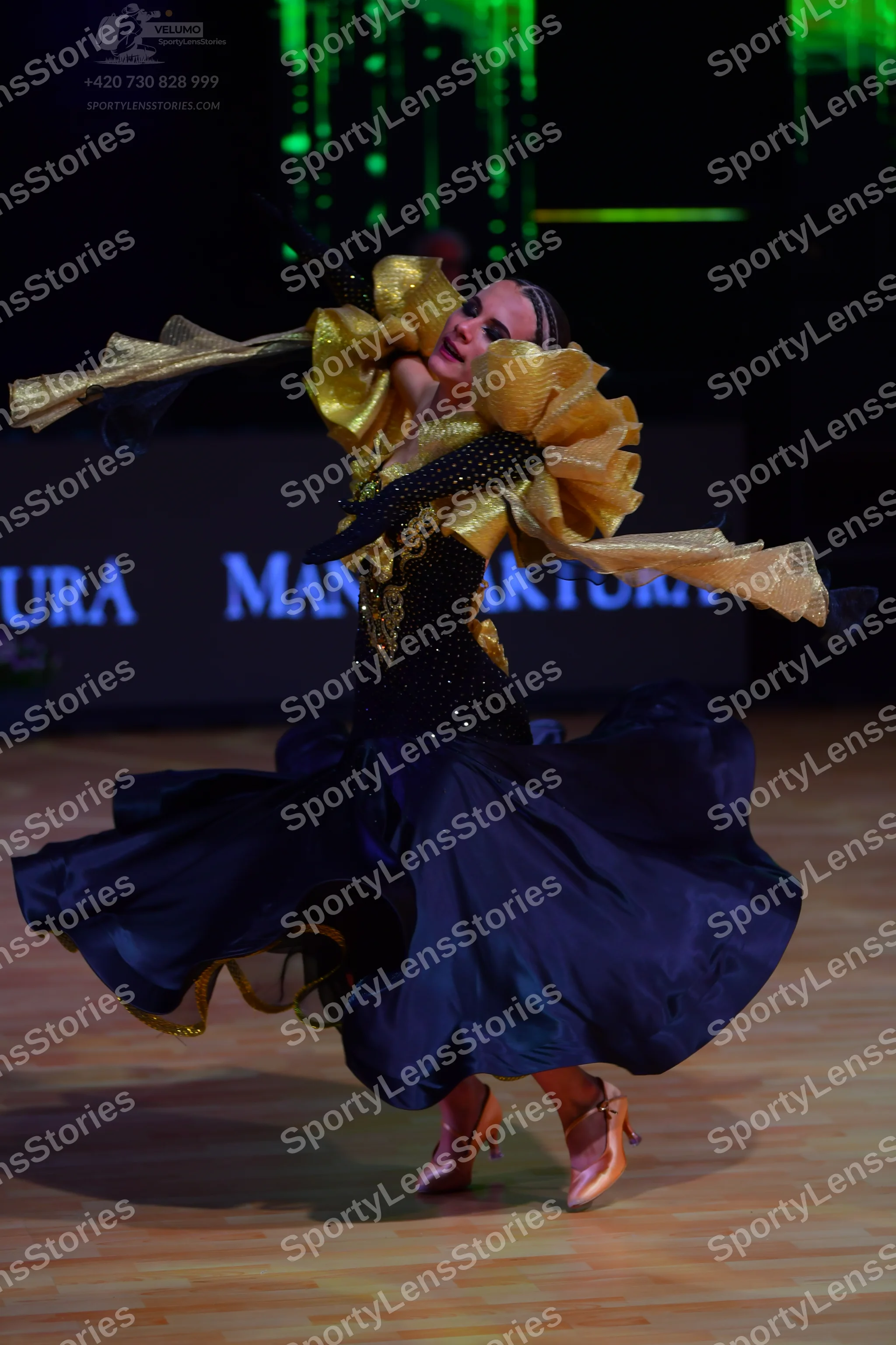 Dancesport competitor: Female dancer: navy blue ballroom gown with a black bodice featuring gold sequin