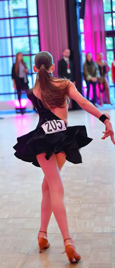 Dancesport competitor #205: Female dancer in foreground: black backless Latin dress with a flared skirt and 