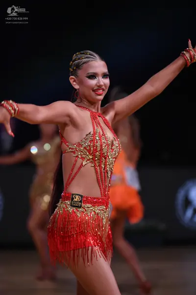 Dancesport competitor: Female dancer: red latin dress with gold sequins and long fringe