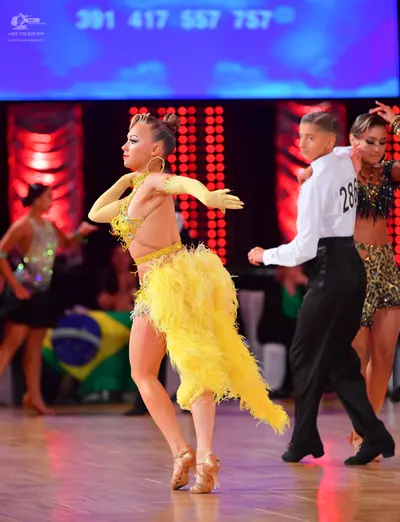 Dancesport competitor #286: Female dancer 1: yellow Latin dress with a sequined bodice and a large, fluffy f
