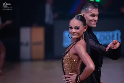 Dancesport competitor: Female dancer: gold sequined Latin dress and large hoop earrings