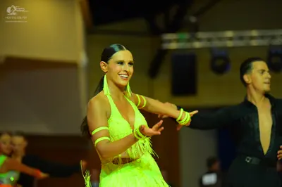 Dancesport competitor: Female dancer: lime green latin dance dress with fringe and matching armbands