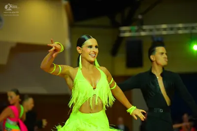 Dancesport competitor: Female dancer: neon yellow Latin dress with fringe on the bodice and skirt, and 