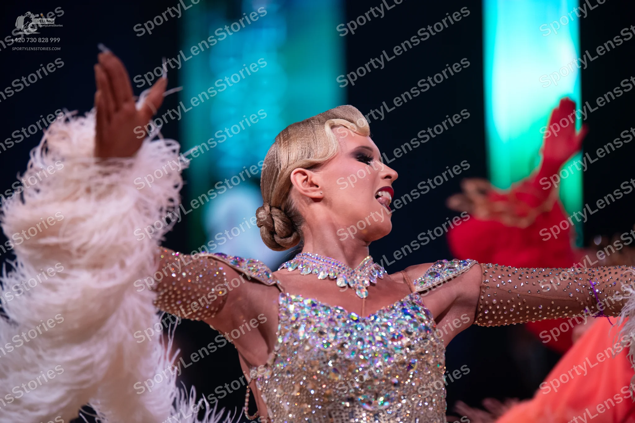 Dancesport competitor: Female dancer in foreground: silver latin dress heavily embellished with sequins