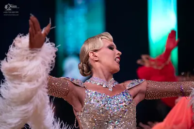 Dancesport competitor: Female dancer in foreground: silver latin dress heavily embellished with sequins