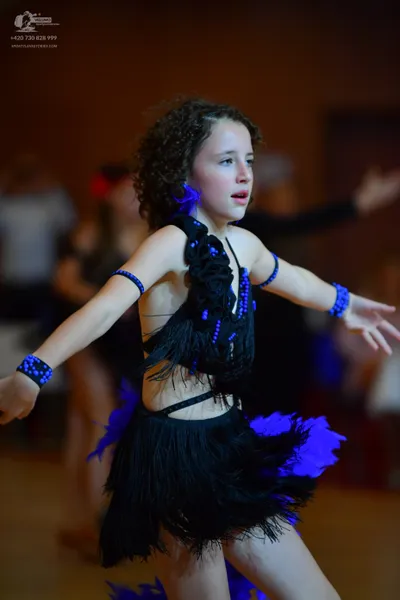 Dancesport competitor: Female dancer: black Latin dress with fringe and blue/purple embellishments