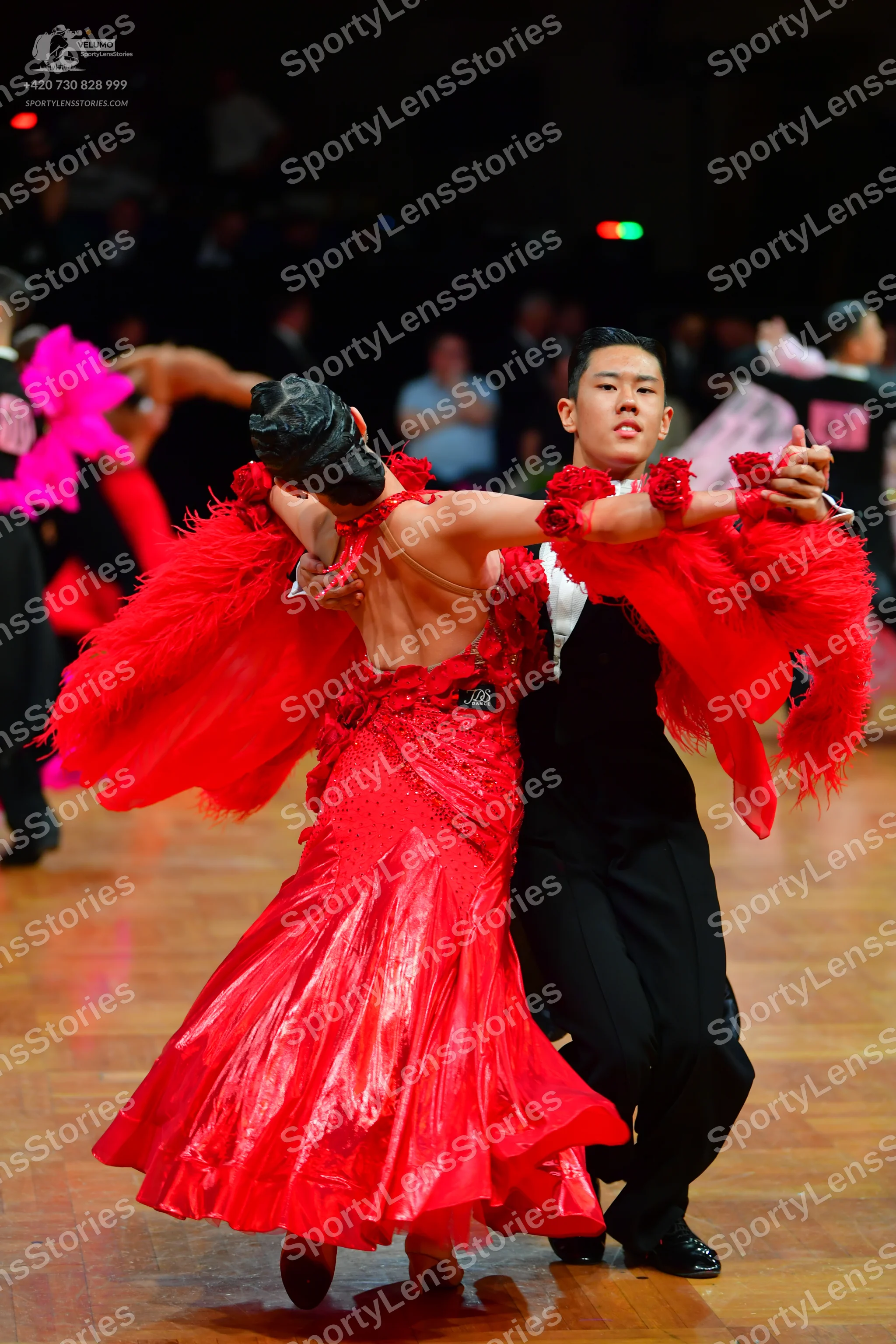Dancesport competitor: Female dancer: red Latin dress with large, voluminous red feathery or fringed sl