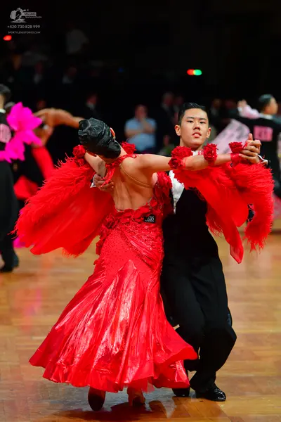 Dancesport competitor: Female dancer: red Latin dress with large, voluminous red feathery or fringed sl