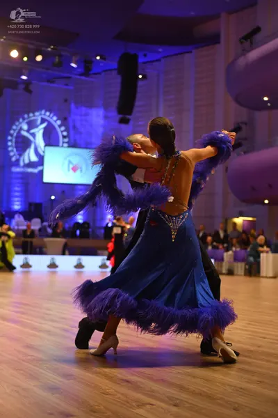 Dancesport competitor: Female dancer: blue latin dress with purple feathers and rhinestone embellishmen