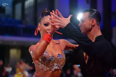 Dancesport competitor: Female dancer: silver sequined Latin dance top, large orange hoop earrings, and 