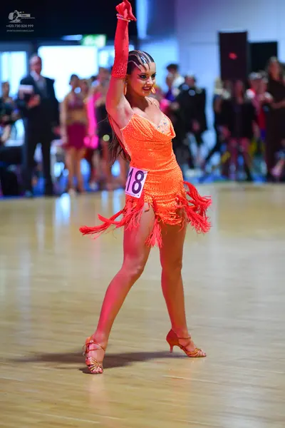 Dancesport competitor #18: Female dancer: orange sequined Latin dress with fringe and matching long orange 