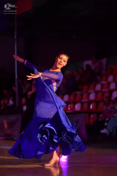 Dancesport competitor: Female dancer: blue ballroom gown with a voluminous ruffled skirt and sheer/mesh