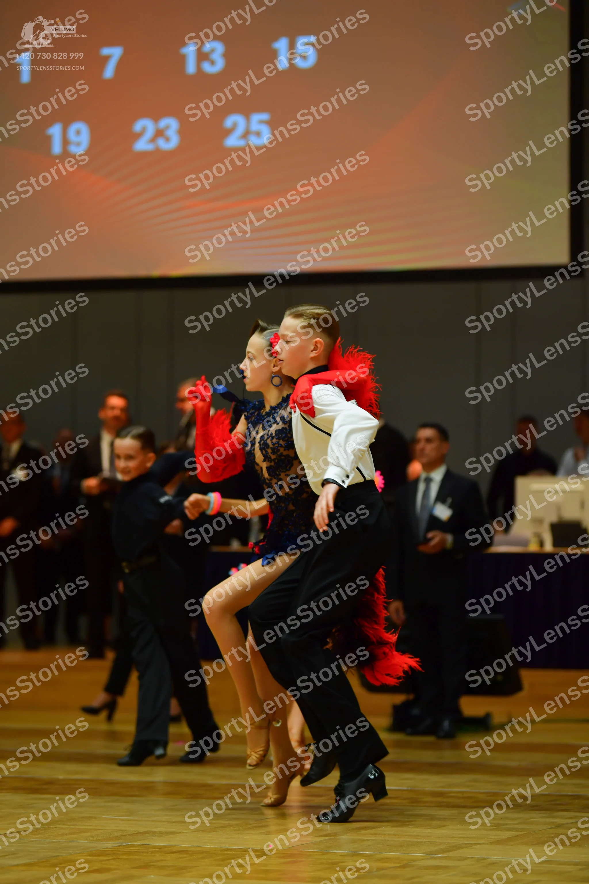 Dancesport competitor: Female dancer: dark lace latin dress with red feather-like accents