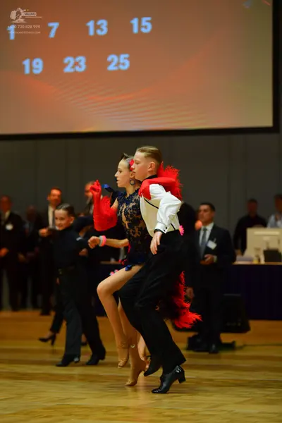 Dancesport competitor: Female dancer: dark lace latin dress with red feather-like accents