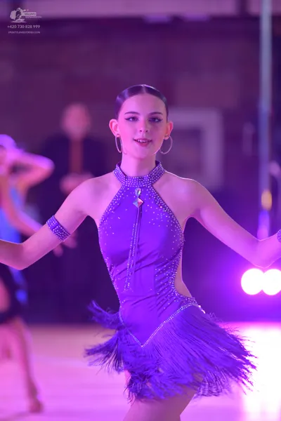 Dancesport competitor: Female dancer in foreground: purple Latin dress with rhinestone embellishments, 