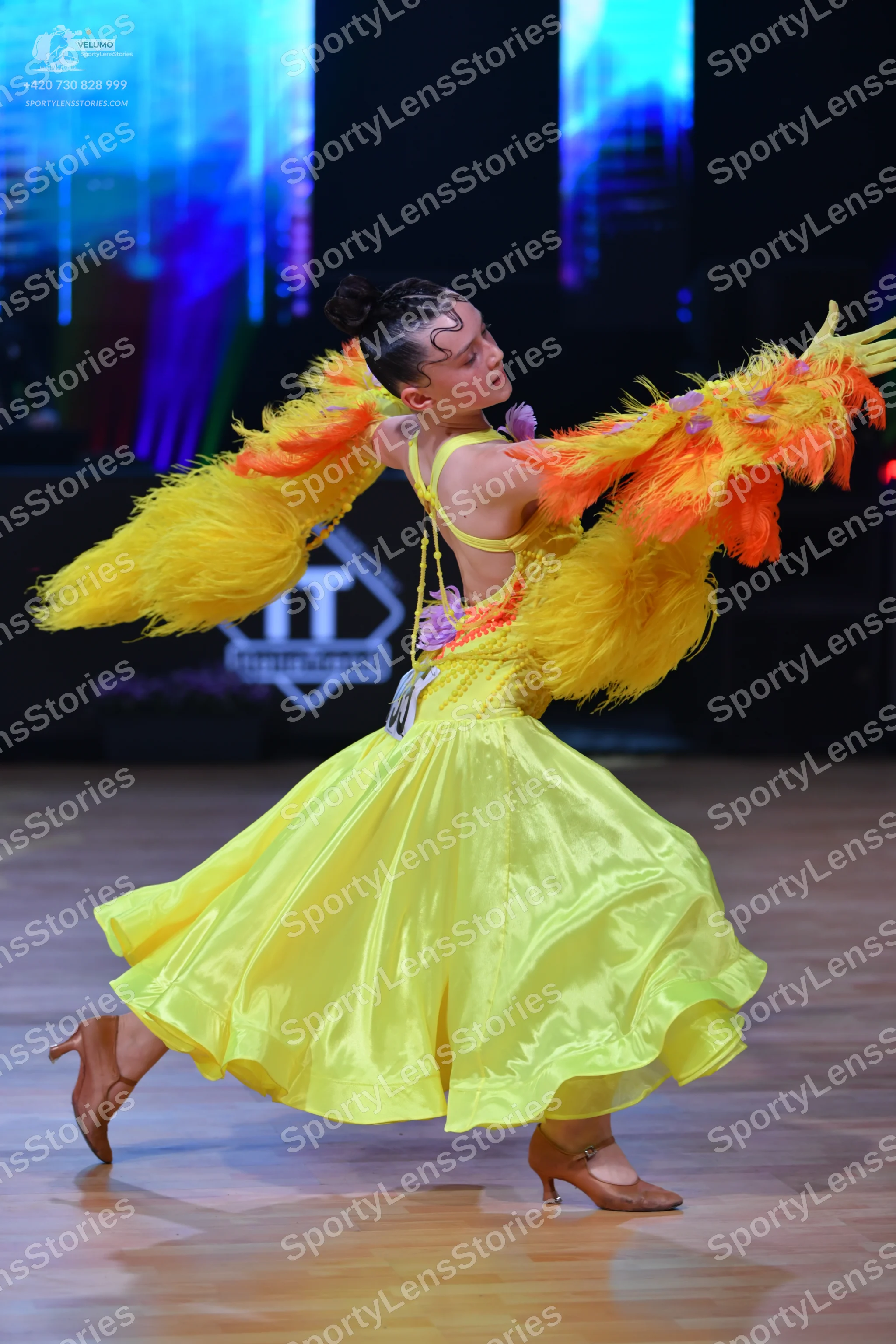 Dancesport competitor: Female dancer: bright yellow latin dress with large, voluminous yellow and orang