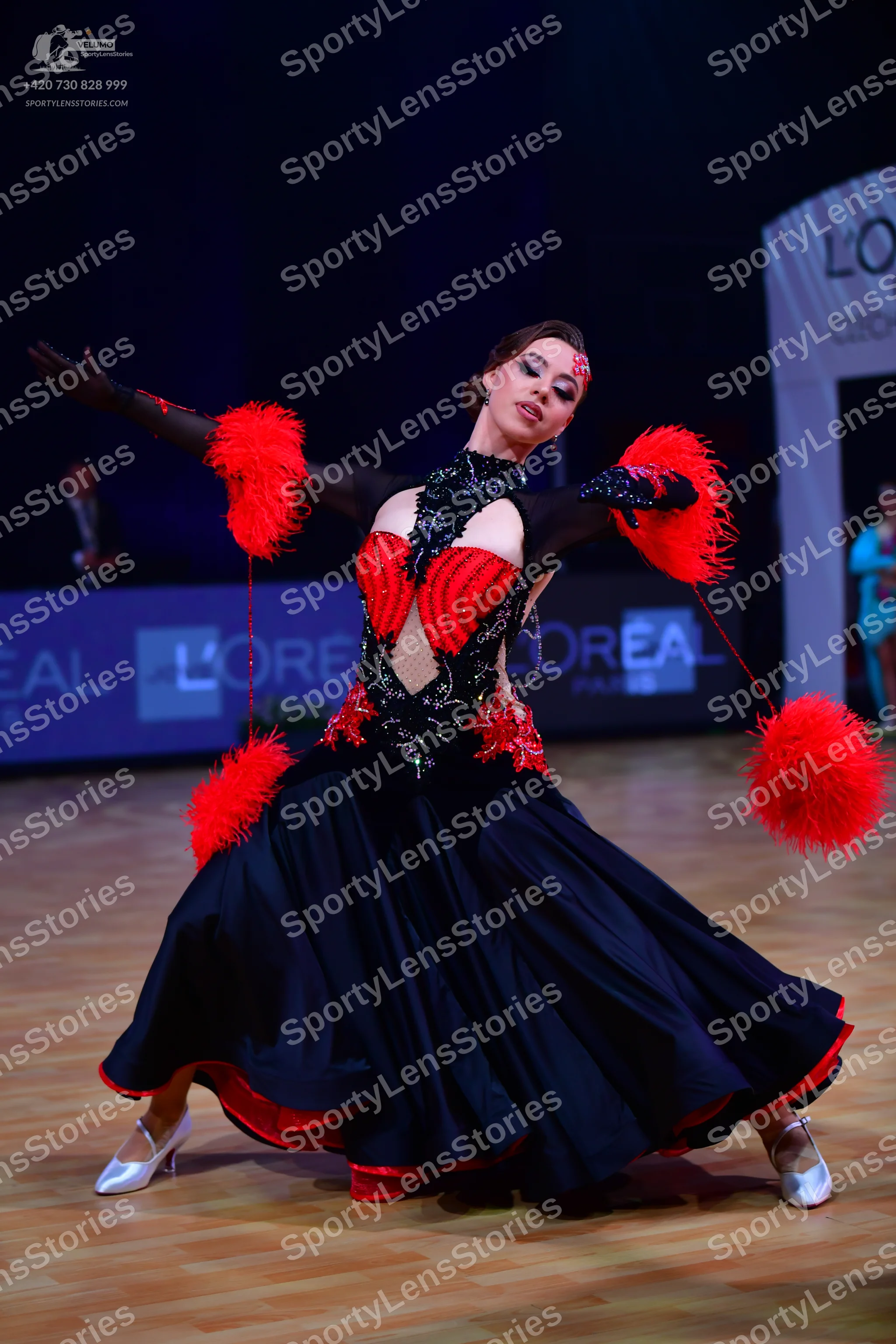 Dancesport competitor: Female dancer: black ballroom gown with red accents, featuring a black lace/sequ