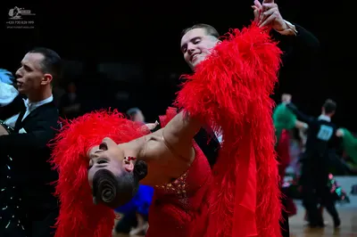 Dancesport competitor: Female dancer: red Latin dress with heavy red fringe and rhinestone embellishmen