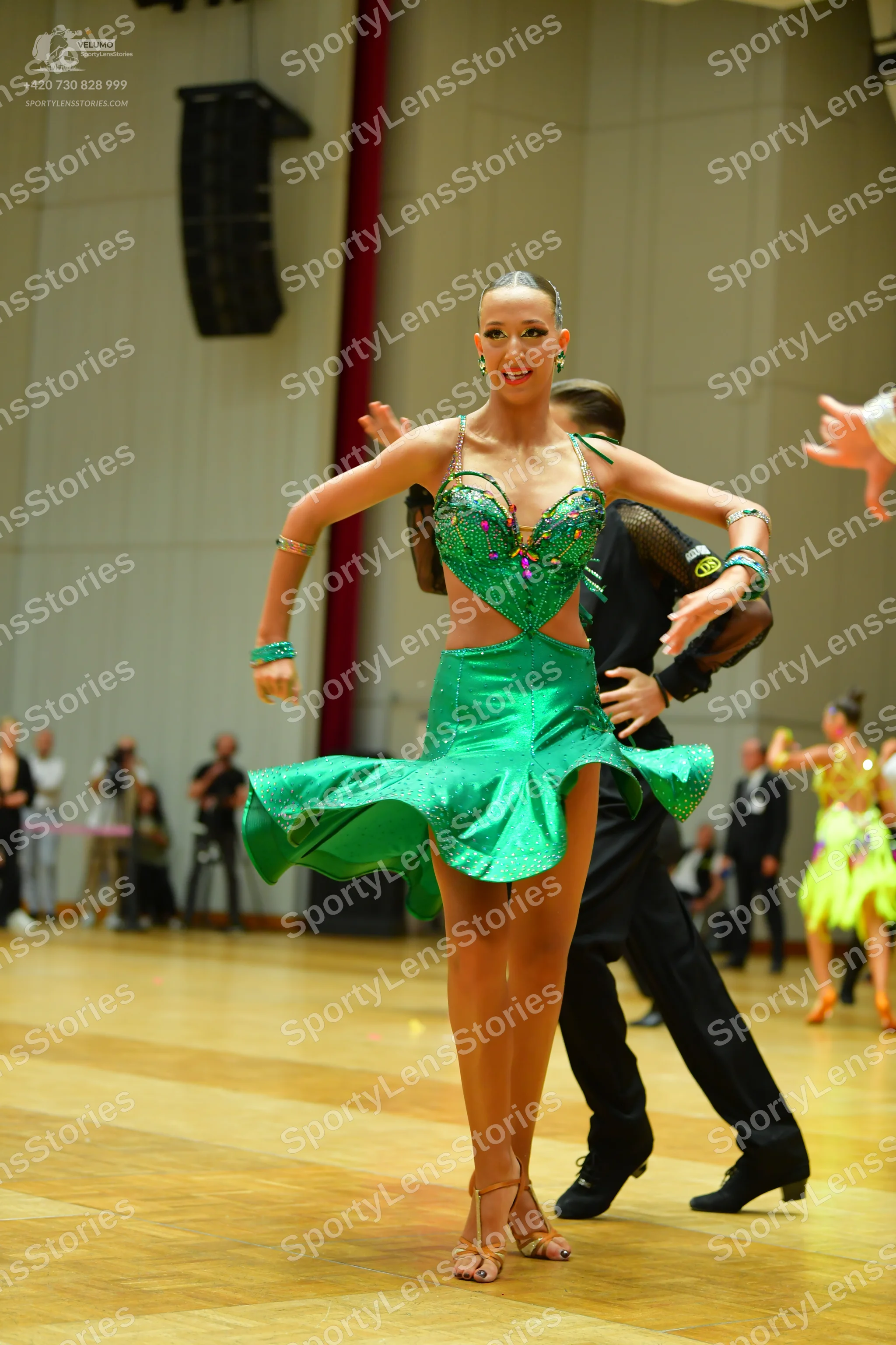 Dancesport competitor: Main female dancer: green latin dress with sequin embellishments and green brace