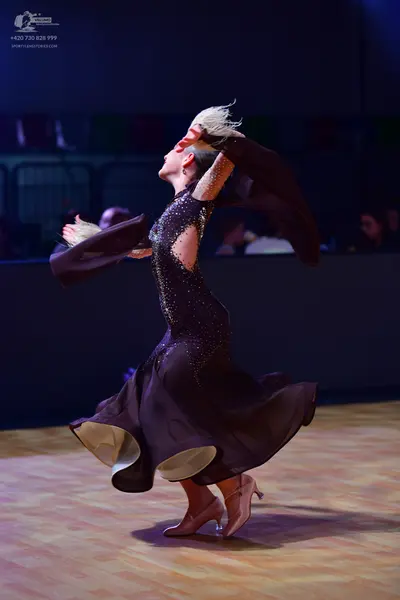Dancesport competitor: Female dancer: black ballroom dress with a sequined bodice and a large, flowing 