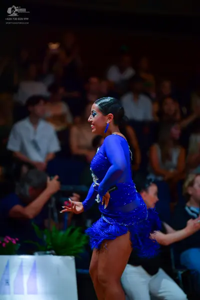 Dancesport competitor: Female dancer: blue latin dress with long sleeves, sequins, and fringe