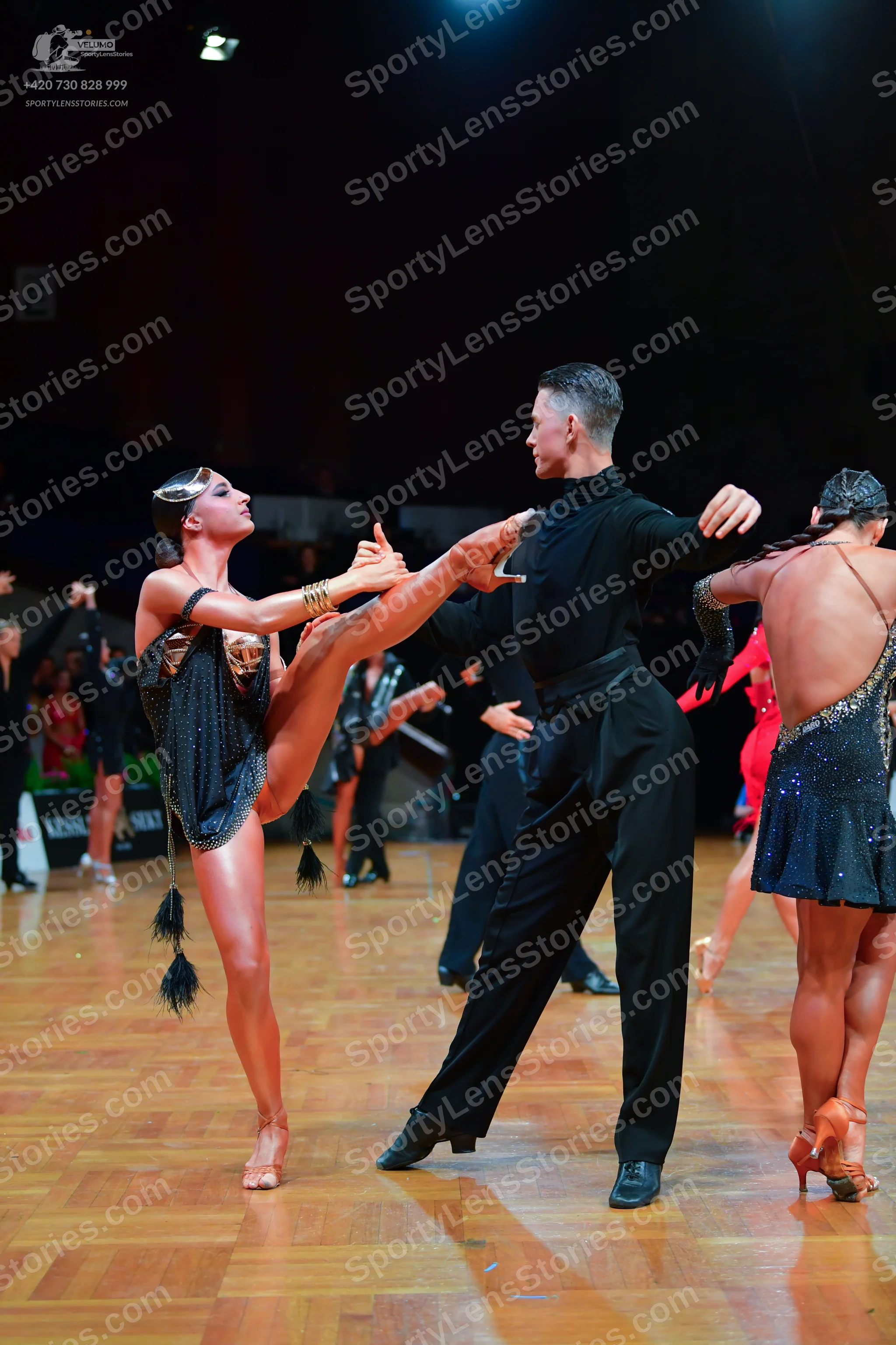 Dancesport competitor: Female dancer (left): dark, sequined Latin dance costume with long black fringe 