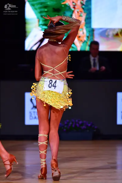 Dancesport competitor: Female dancer: yellow Latin dress with sequins and fringe, featuring a criss-cro