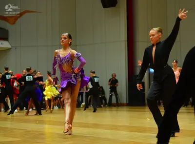 Dancesport competitor: Female dancer (foreground): purple latin dress with silver sequin embellishments