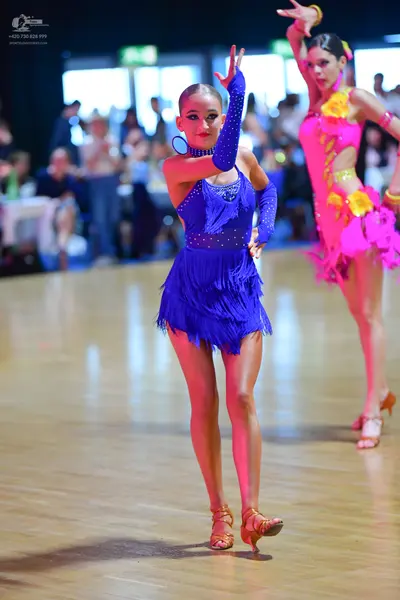 Dancesport competitor: Female dancer 1: blue latin dress with sequins and fringe, and a single long blu