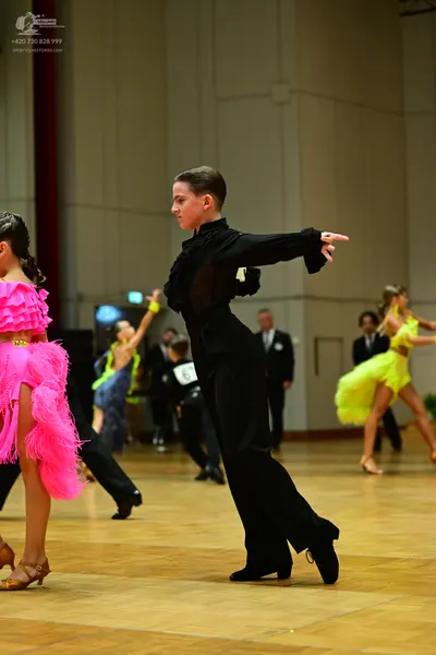 Dancesport competitor: Female dancer (foreground): bright pink latin dress with voluminous ruffles