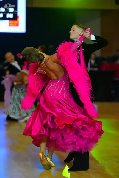 Dancesport competitor: Main female dancer: bright pink Latin dress with a heavily ruffled skirt, rhines