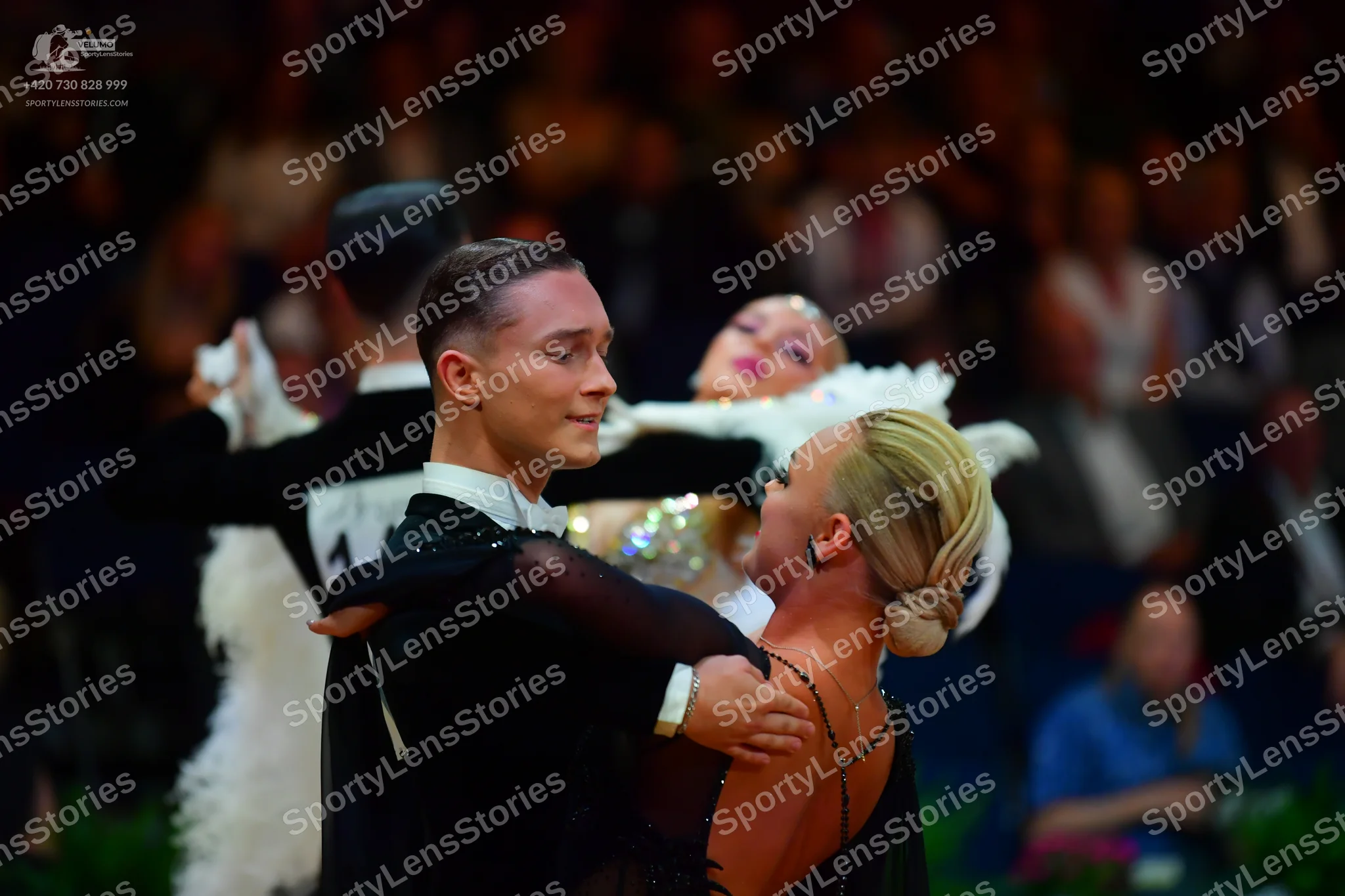 Dancesport competitor: Foreground male dancer: black long-sleeved dance shirt