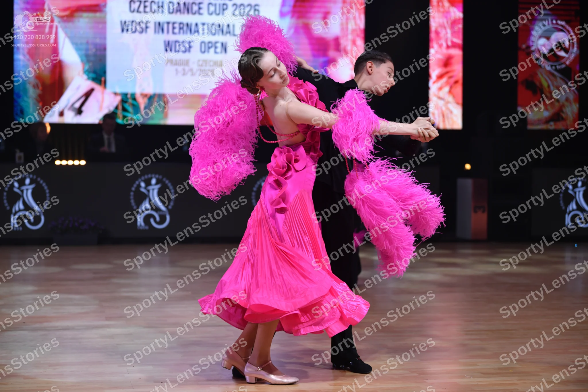 Dancesport competitor: Female dancer: bright pink Latin dance dress with large, voluminous pink feather