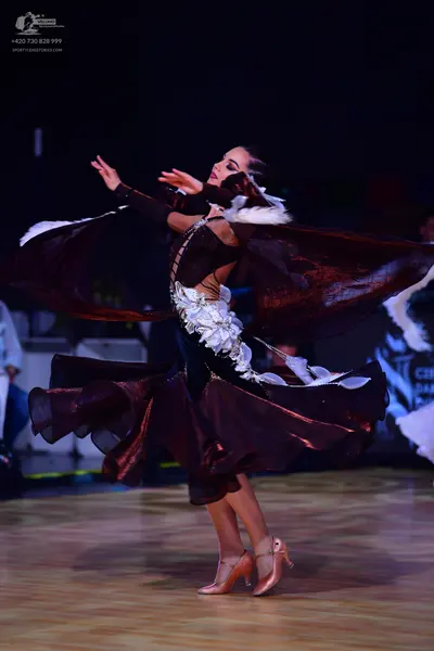 Dancesport competitor: Female dancer: dark burgundy-colored ballroom dress with a large, voluminous, fl