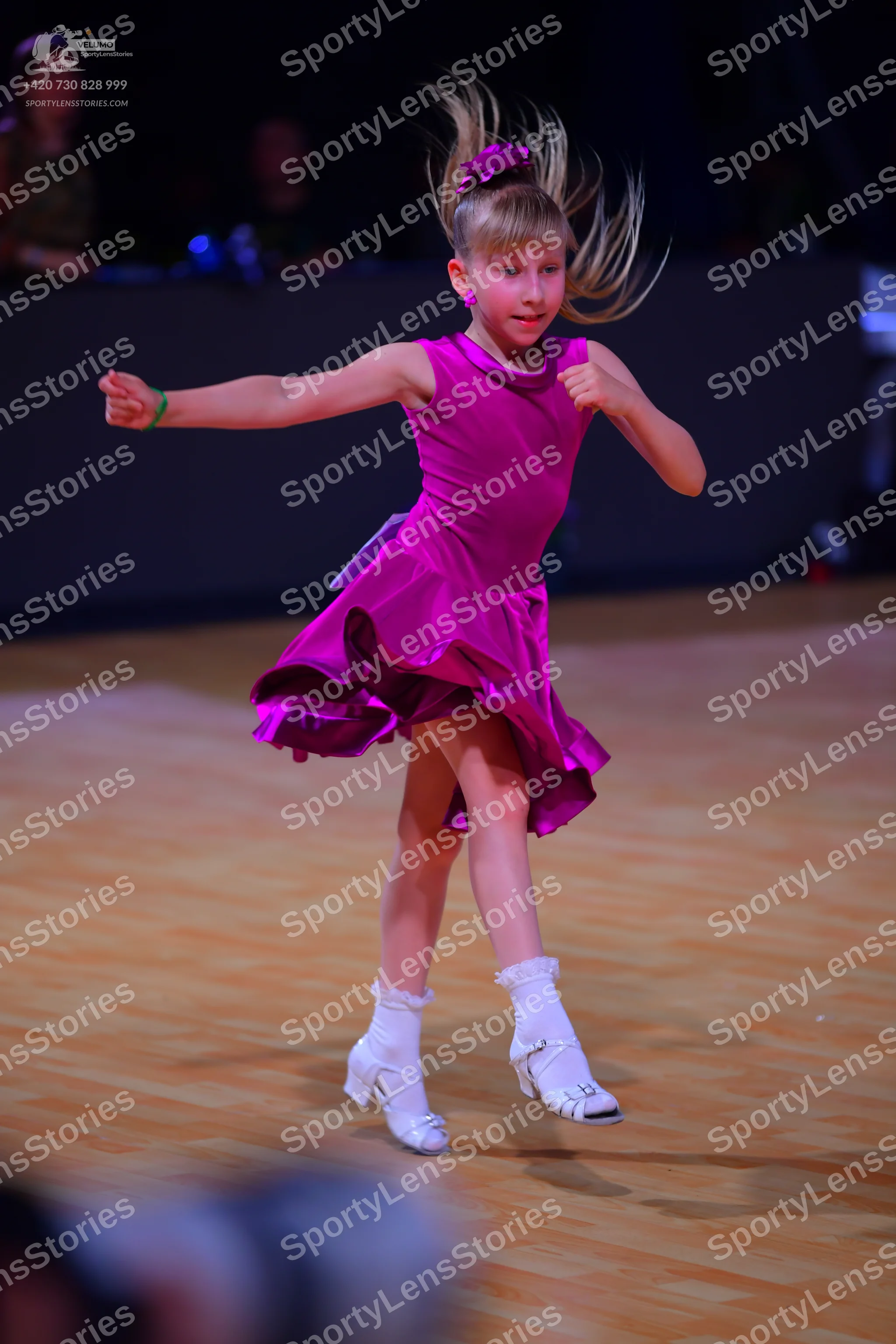 Dancesport competitor: Female dancer: magenta satin-like latin dress with a flared, ruffled skirt and h