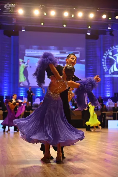 Dancesport competitor: Foreground female dancer: purple latin dress with a sequined/beaded bodice and l