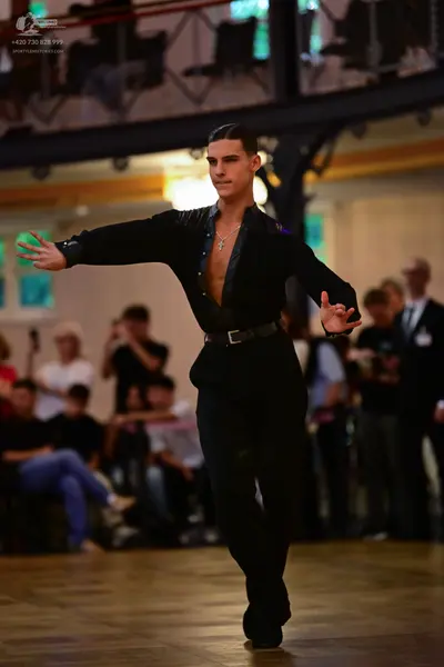 Dancesport competitor: Male dancer: black long-sleeved shirt, unbuttoned, and black trousers with a bla