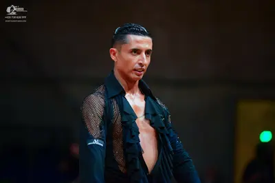 Dancesport competitor: Male dancer: black latin dance shirt with mesh sleeves and ruffled details on th