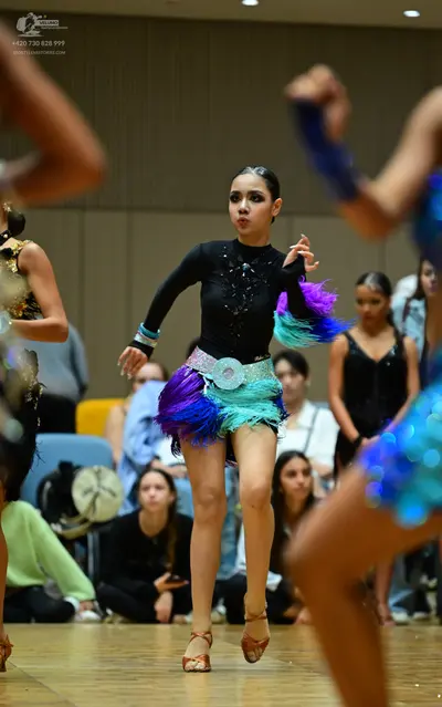 Dancesport competitor: Female dancer (center): black long-sleeve latin dress with sequin embellishments
