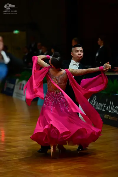 Dancesport competitor: Female dancer: bright pink ballroom dress with a sheer bodice decorated with sil