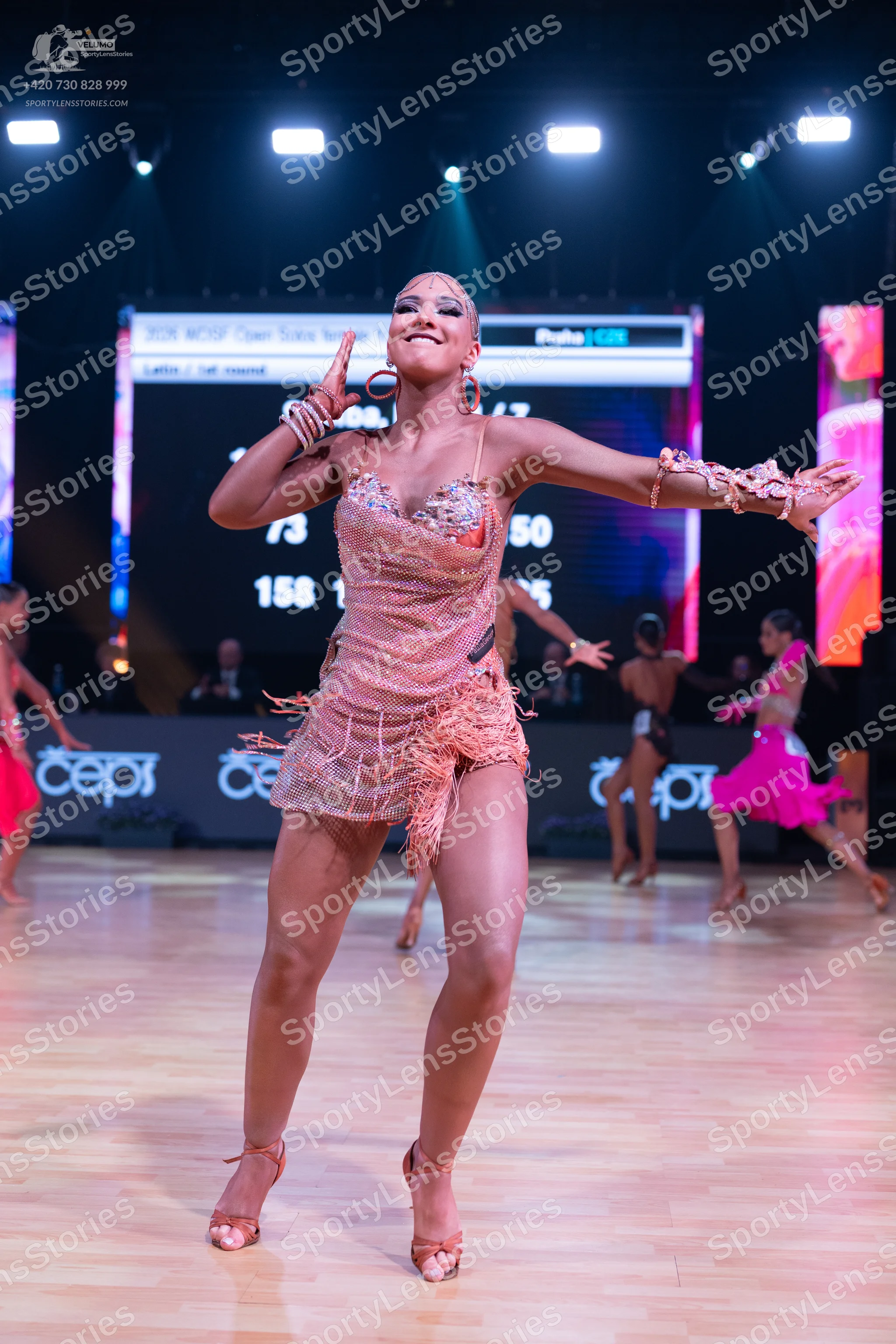 Dancesport competitor: Main dancer: rose gold/nude Latin dress with sequins, fringe, and thin straps, a